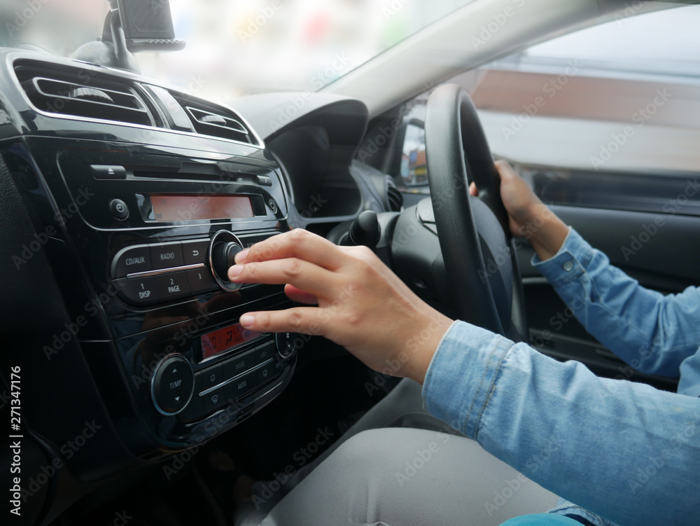 Female Driver's Hand Press Button on Car Radio
