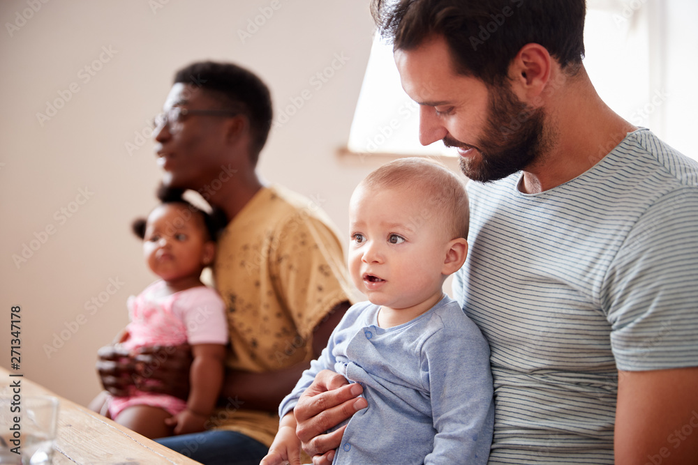 Two Families With Babies Meeting And Talking Around Table On Play Date Two Families With Babies Meeting And Talking Around Table On Play Date