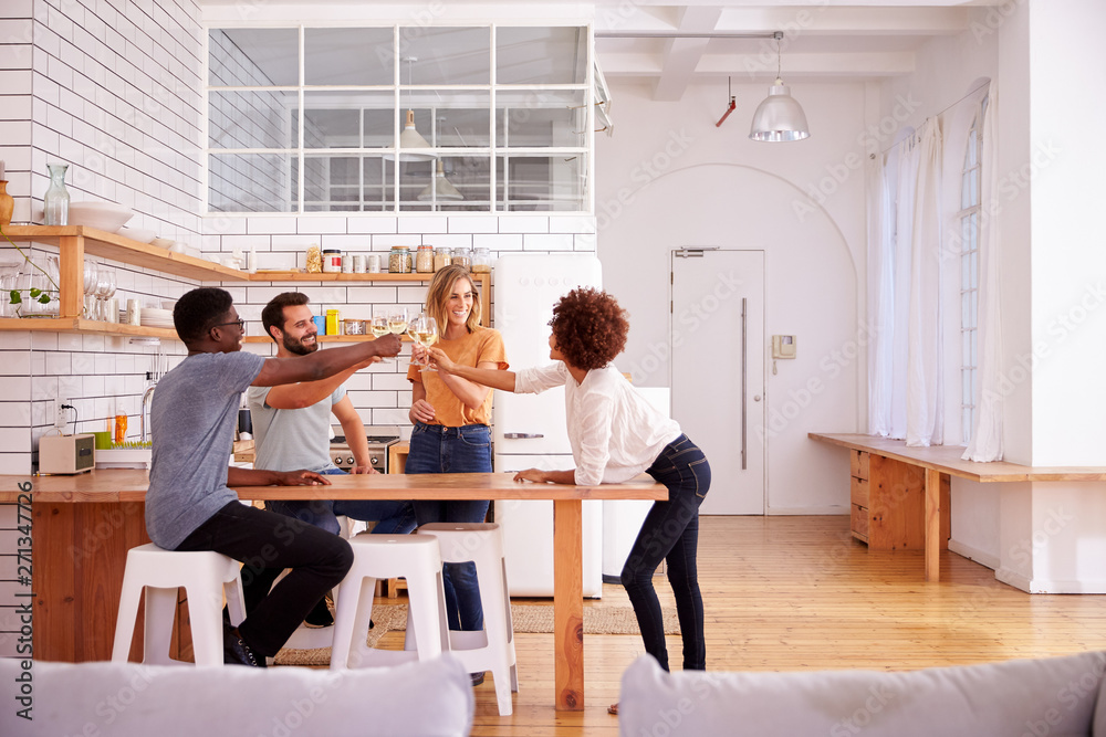 Two Couples Relaxing In Kitchen At Home Making A Toast With Glass Of Wine Together Two Couples Relaxing In Kitchen At Home Making A Toast With Glass Of Wine Together