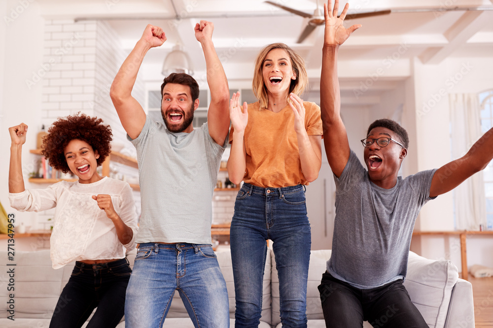 Fototapeta premium Excited Group Of Friends Sitting On Sofa Watching Sports On TV And Celebrating