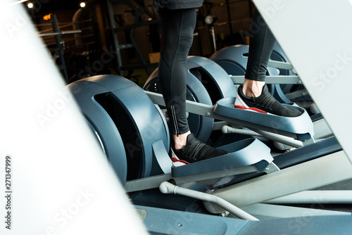 cropped view of athletic man working out on exercise bike in gym
