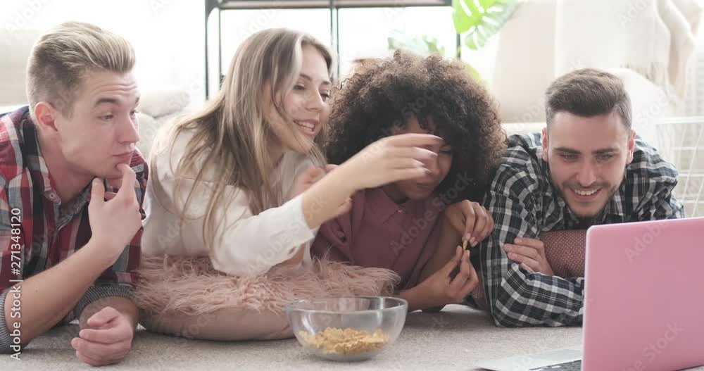 Friends having fun eating snack and watching movie on laptop Friends having fun eating snack and watching movie on laptop
