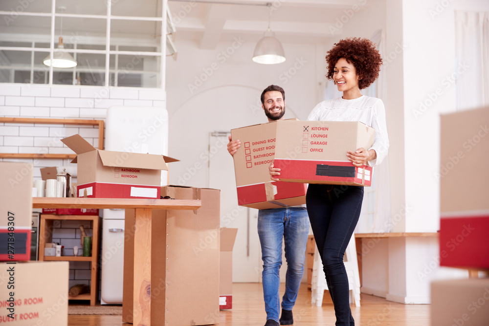 Smiling Couple Carrying Boxes Into New Home On Moving Day Smiling Couple Carrying Boxes Into New Home On Moving Day