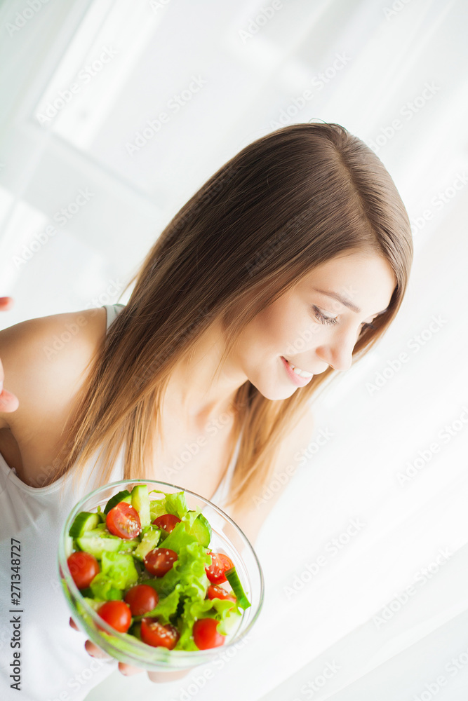 Diet. Young woman eating salad and holding a mixed salad