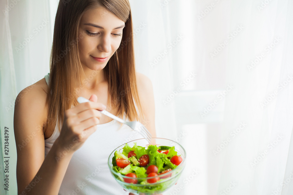 Diet. Young woman eating salad and holding a mixed salad Diet. Young woman eating salad and holding a mixed salad
