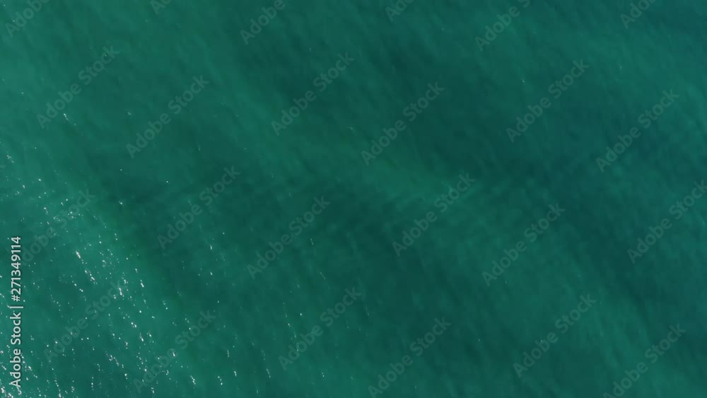 Aerial top down view from high altitude of green sea water texture. The camera flies over the water, a view of the water surface. Background of the water surface. 4K aerial view