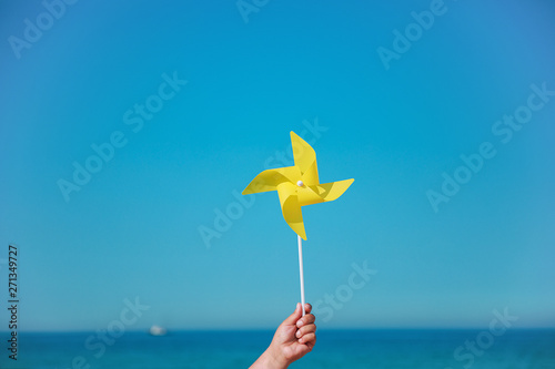 Hand holding yellow pinwheel in the sea
