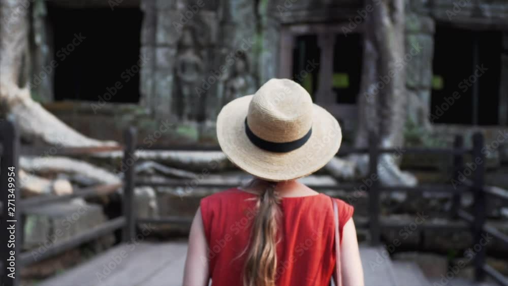 Following caucasian woman exloring Ta Prohm temple and taking photo of iits exterior including giant banyan roots growing on its gallery. Cambodia Following caucasian woman exloring Ta Prohm temple and taking photo of iits exterior including giant banyan roots growing on its gallery. Cambodia