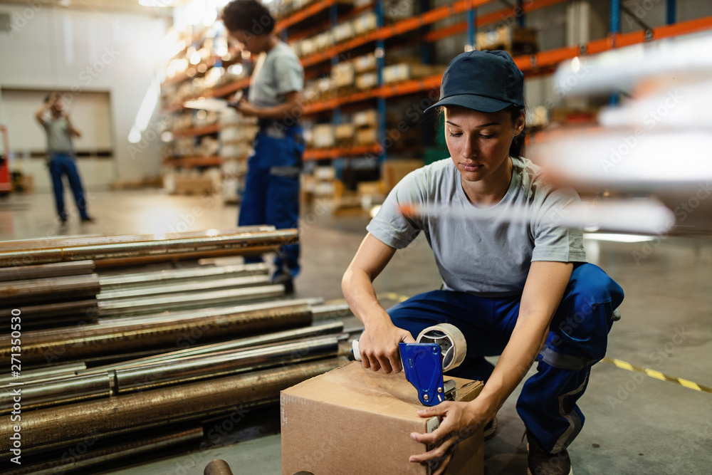 Young worker using tape dispenser gun while packing boxes in distribution warehouse. Young worker using tape dispenser gun while packing boxes in distribution warehouse.