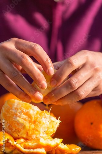 Woman peels oranges from peel.