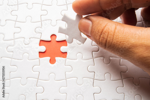 hand holding piece of blank jigsaw puzzle for copy space, replacement words or text. Close up selective focus.