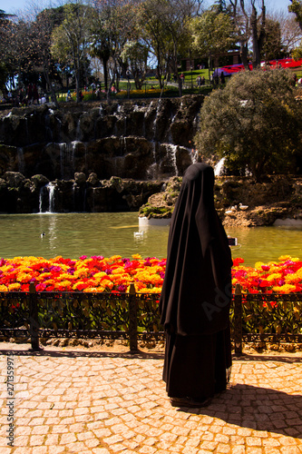 Woman dressed in black hijab filming in  park photo