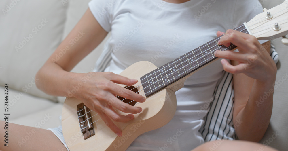 Naklejka premium Woman play ukulele at home