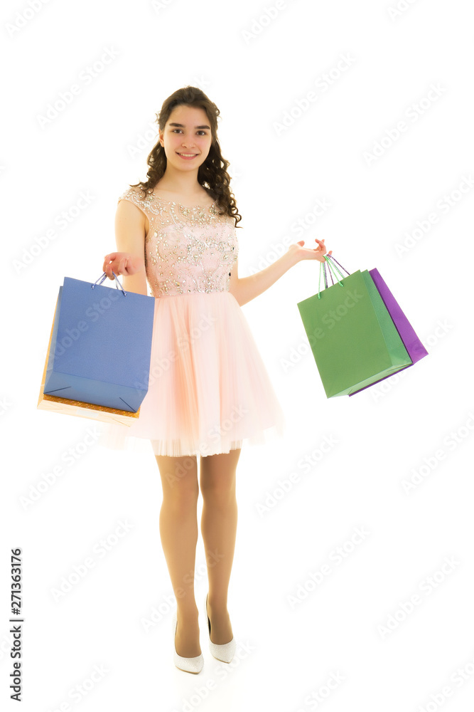 Teenager girl shopping in a store with large paper bags.