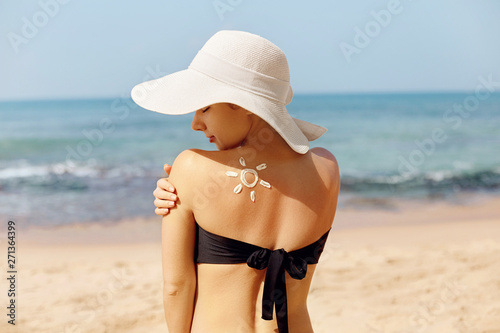 Woman apply sun cream protection cream on her  tanned Shoulder. Beautiful Girl on a beach.Sun Protection.Sun Cream. Skin and Body Care.Portrait Of Female Holding Moisturizing Sunblock.