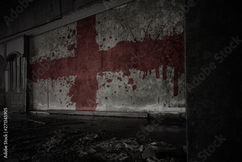 painted flag of england on the dirty old wall in an abandoned ruined house. photo