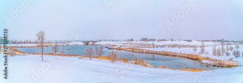 Idyllic winter scenery with a calm silvery lake amid a snow covered landscape