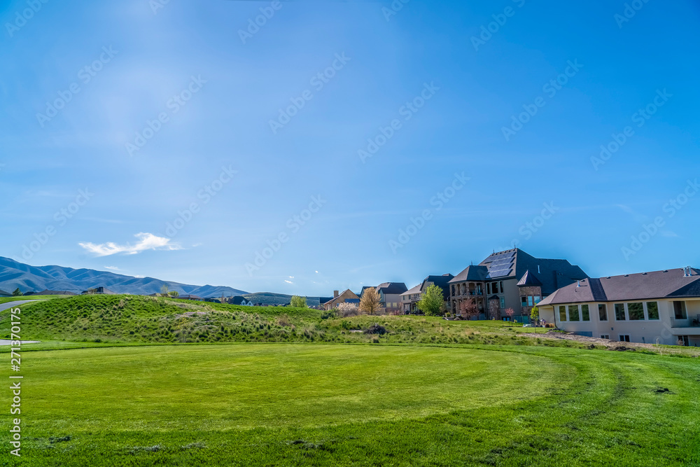 Residential houses on a terrain with vivid green grasses viewed on a sunny day Residential houses on a terrain with vivid green grasses viewed on a sunny day