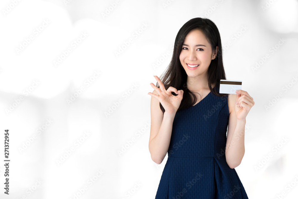 Young smiling beautiful Asian woman showing credit card with okey gesture Young smiling beautiful Asian woman showing credit card with okey gesture