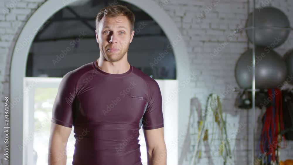 Cheerful muscular man waving at camera and telling about dietary supplements while recording video in gym for sports vlog Cheerful muscular man waving at camera and telling about dietary supplements while recording video in gym for sports vlog