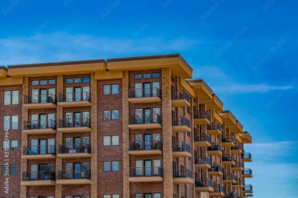 Residential brick building with balconies against blue sky with thin clouds