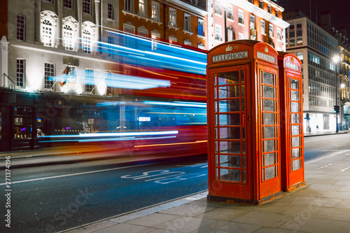 Light trails of a double decker bus next to the iconic telephone booth in London photo