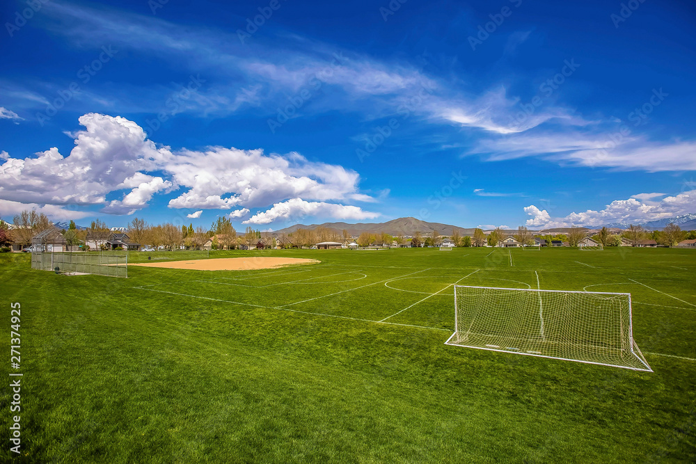 Panorama of a soccer field with houses and mountain in the distance