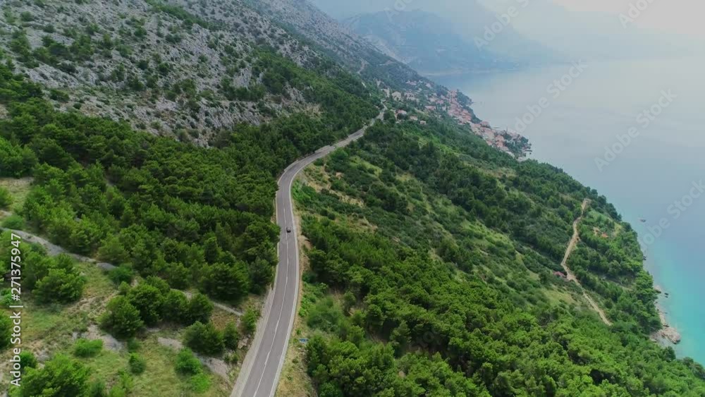 aerial shot of coastal highway in Croatia with camera lifting up movement following the car on highway