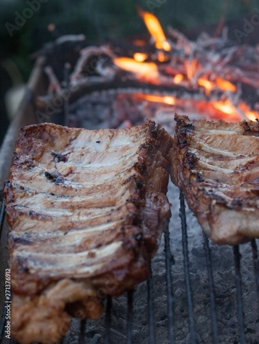 Grilled barbeque port. Cooking outdoor. Marinated grilled ribs. Summer picnic. Cooking dinner. Spareribs Ribs Close-up On The Hot Flaming Grill.