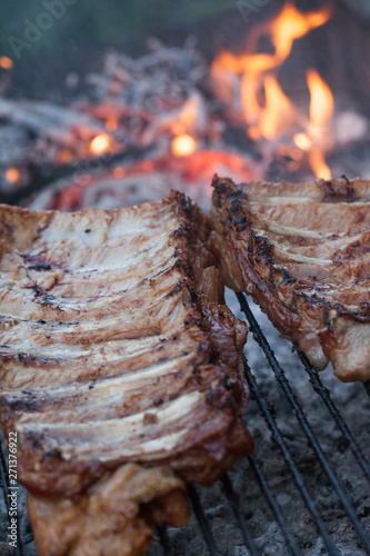 Grilled barbeque port. Cooking outdoor. Marinated grilled ribs. Summer picnic. Cooking dinner. Spareribs Ribs Close-up On The Hot Flaming Grill.