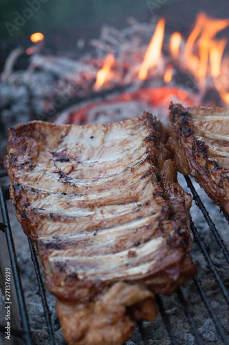 Grilled barbeque port. Cooking outdoor. Marinated grilled ribs. Summer picnic. Cooking dinner. Spareribs Ribs Close-up On The Hot Flaming Grill.