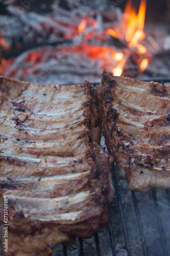 Grilled barbeque port. Cooking outdoor. Marinated grilled ribs. Summer picnic. Cooking dinner. Spareribs Ribs Close-up On The Hot Flaming Grill.