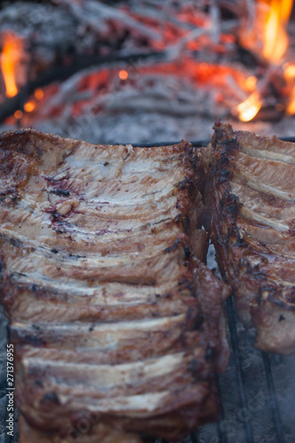 Grilled barbeque port. Cooking outdoor. Marinated grilled ribs. Summer picnic. Cooking dinner. Spareribs Ribs Close-up On The Hot Flaming Grill.