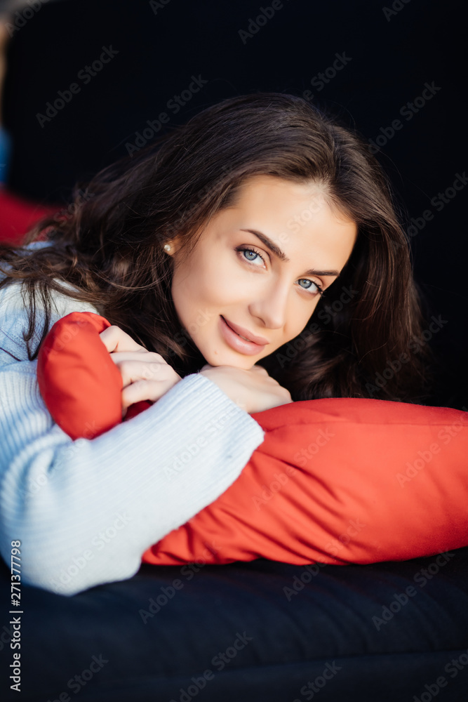 Brunette young woman hugging a pillow sitiing on sofa. Brunette young woman hugging a pillow sitiing on sofa.