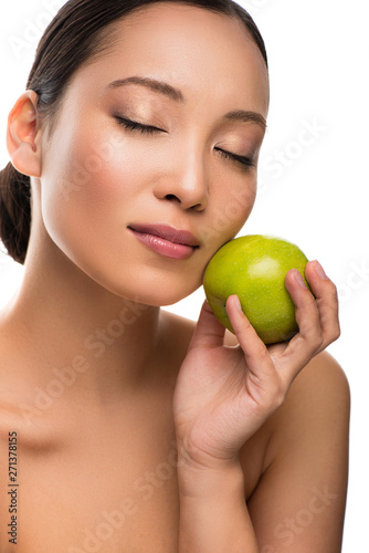 tender asian woman with closed eyes holding green apple, isolated on white