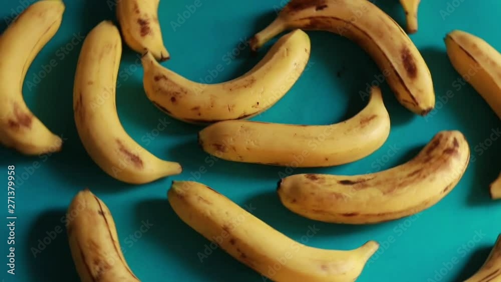 A macro shot of ripe yellow organic bananas rotating against a green background. A macro shot of ripe yellow organic bananas rotating against a green background.
