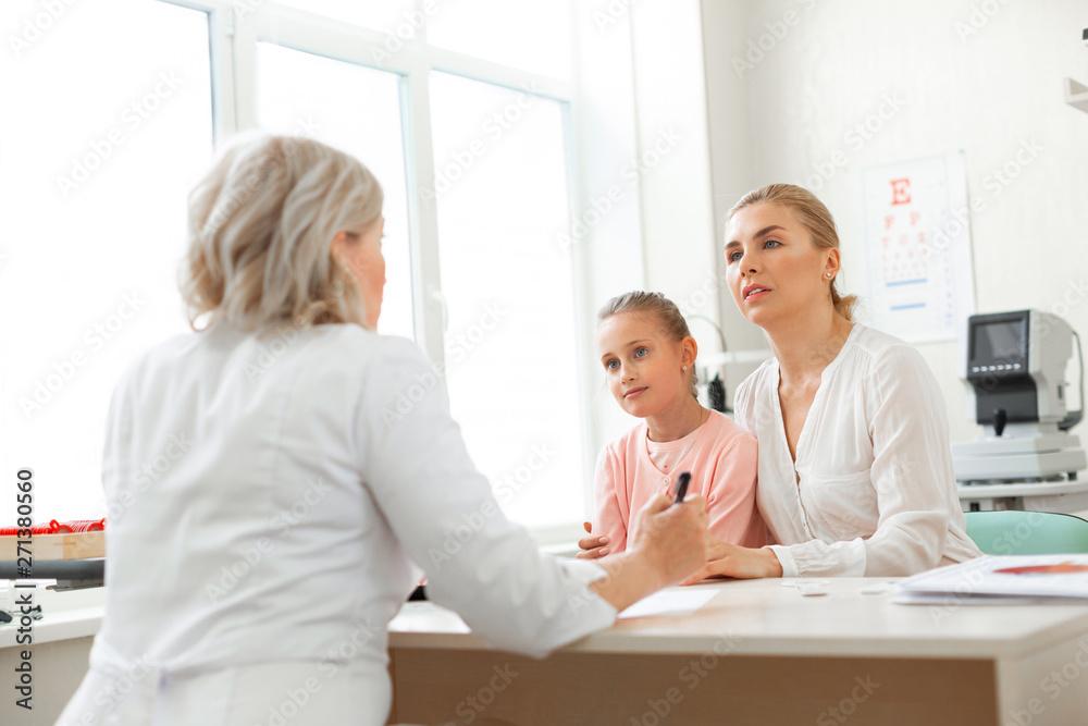 Focused blonde lady hugging her daughter while listening