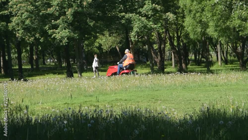 the working on a tractor lawn mower in the Park mowing the grass the working on a tractor lawn mower in the Park mowing the grass