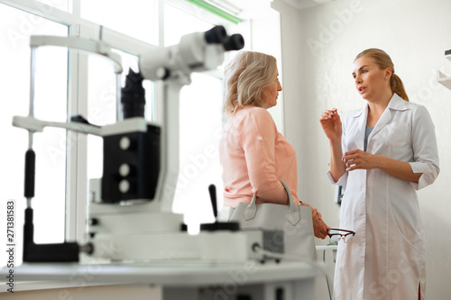 Diligent long-haired ophthalmologist actively gesturing while talking