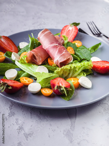 Delicious salad with greens, strawberries, bresaola, lumps and mozzarella. Tasty and healthy. Italian salad. Close up