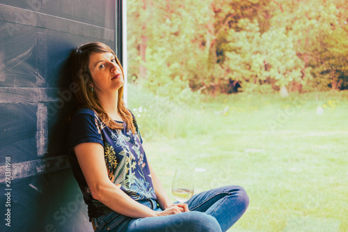 woman with a glass of wine sitting nearby the the window on a lazy summer day