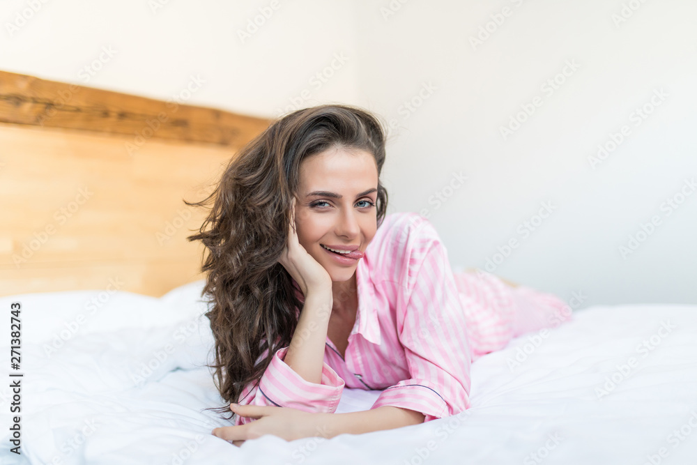 Young woman lying in bed, wearing modern cozy cotton pajamas, modern decoration bedroom Young woman lying in bed, wearing modern cozy cotton pajamas, modern decoration bedroom