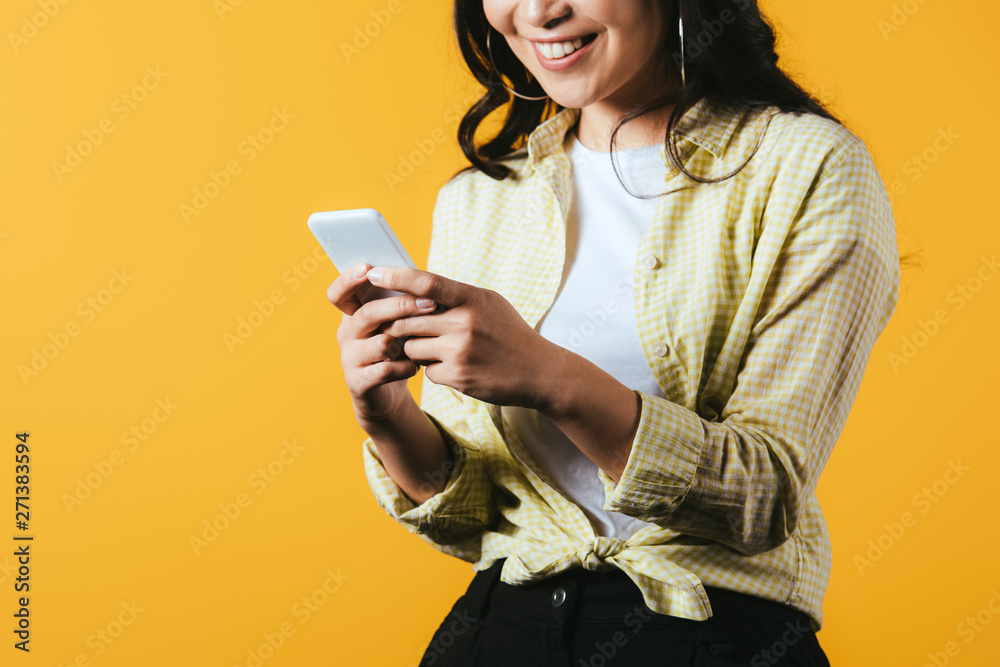 cropped view of happy girl using smartphone isolated on yellow