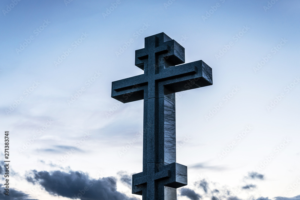 stone Christian cross on blue sky	