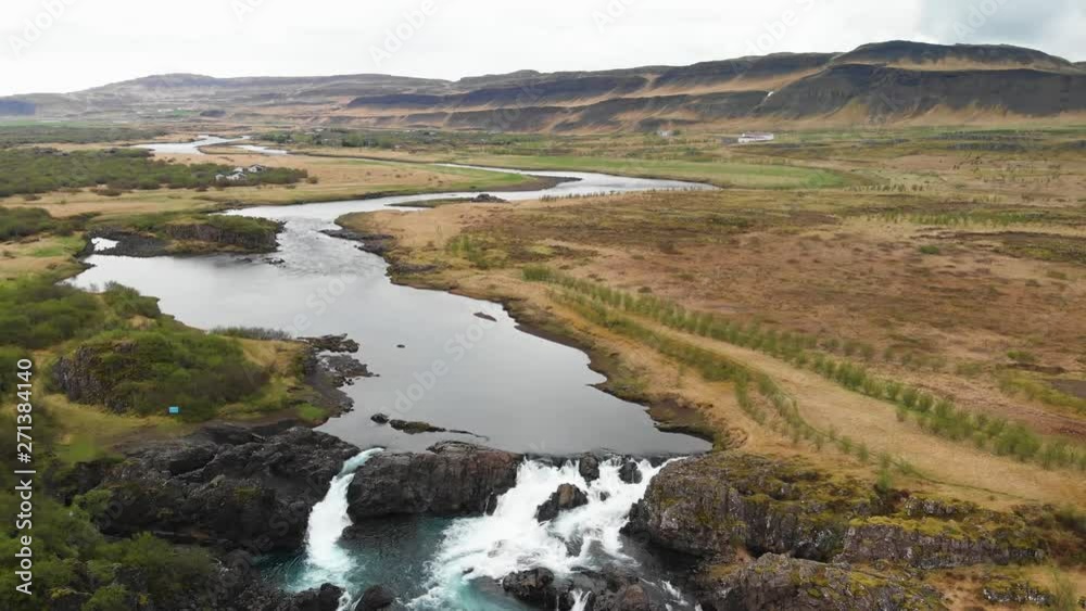 The less crowded but beautiful waterfall Glanni seen from above, surrounded by a magical Icelandic landscape with lush green bushes and majestic mountains in the background The less crowded but beautiful waterfall Glanni seen from above, surrounded by a magical Icelandic landscape with lush green bushes and majestic mountains in the background