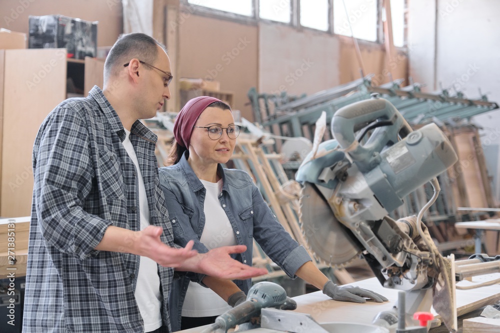 Industrial portrait of two working men and woman, talking at machine tools Industrial portrait of two working men and woman, talking at machine tools