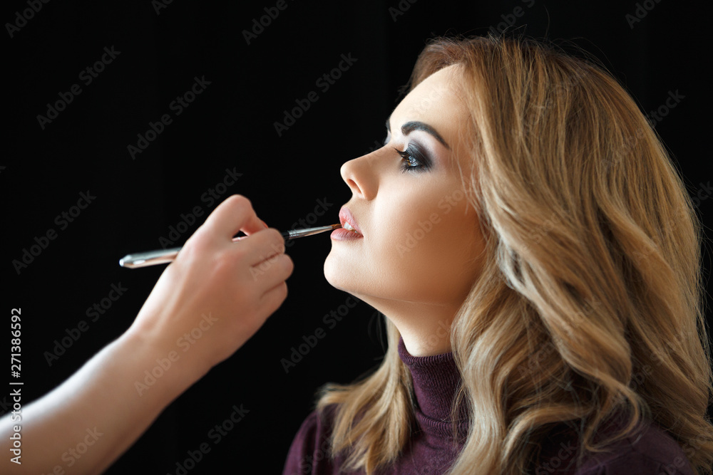 Fototapeta premium Beauty shop. Make up. Hand of stylist paints lips with a brush to client.