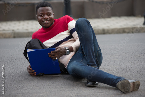 young smiling student studying lying outside