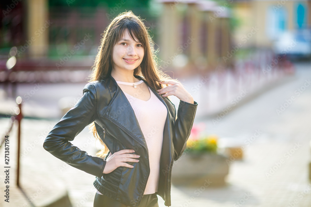 close up portrait of beautiful girl teenager in leather jacket in urban street background