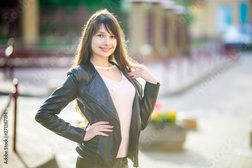 close up portrait of beautiful girl teenager in leather jacket in urban street background © hiv360